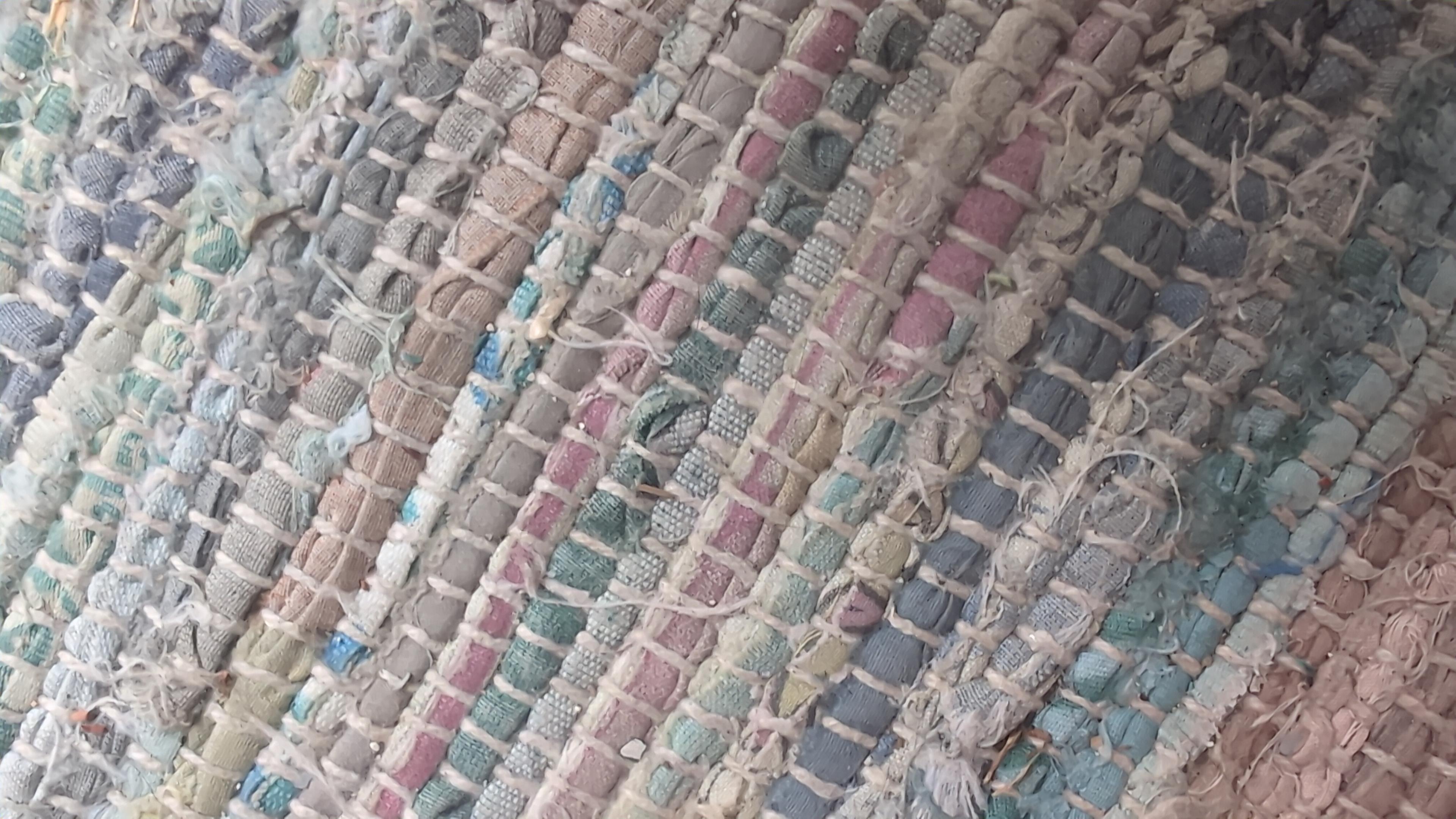 close-up picture of a handmade rug, with multiple crossing lines of colourful fabric.